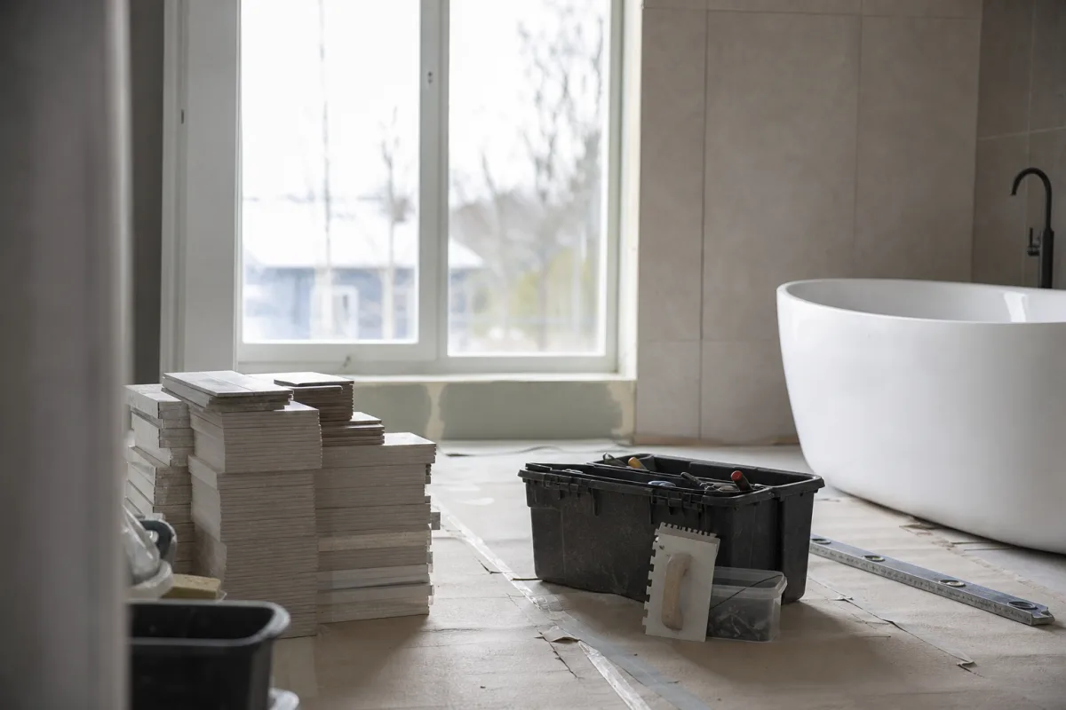 Badrum under renovering med staplade kakelkartonger på skyddat golv